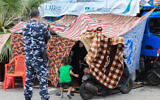 Lebanese security forces members check on displaced people who set up makeshift shelters on Beirut's seaside promenade in order to relocate them on October 10, 2024. (AFP)