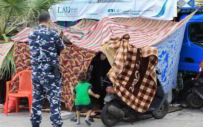 Lebanese security forces members check on displaced people who set up makeshift shelters on Beirut's seaside promenade in order to relocate them on October 10, 2024. (AFP)