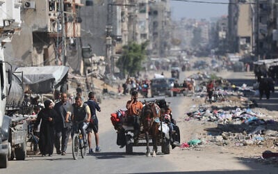 Palestinians transport their belongings as they flee areas north of Gaza City on October 12, 2024. (Omar Al-Qattaa / AFP)