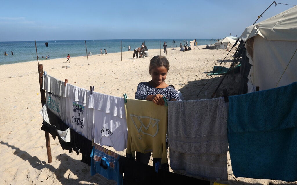 A Palestinian girl hangs clothes outside her displaced family's tent at a makeshift camp on the beach of Gaza City on October 13, 2024 (Eyad BABA / AFP)