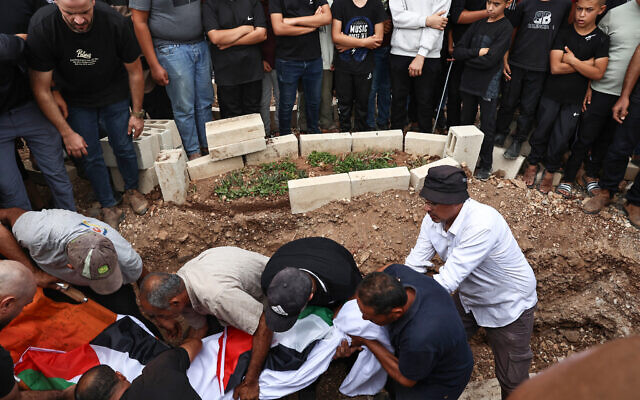 Mourners lower the body of Hanan Abdel Rahman Abu Salama, 59, into a grave, after she was reportedly killed by Israeli fire as she was picking olives in the West Bank village of Faqoua near Jenin, on October 17, 2024. (Zain Jaafar/AFP) Mourners lower the body of Hanan Abdel Rahman Abu Salama, 59, into a grave, after she was reportedly killed by Israeli fire as she was picking olives in the West Bank village of Faqoua near Jenin, on October 17, 2024. (Zain Jaafar/AFP)