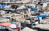 People walk past tents sheltering people displaced by conflict in the Al-Mawasi area of Khan Younis in the southern Gaza Strip on October 23, 2024. (Bashar Taleb / AFP)