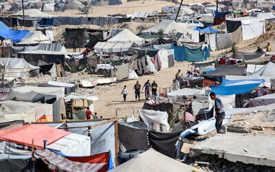People walk past tents sheltering people displaced by conflict in the Al-Mawasi area of Khan Younis in the southern Gaza Strip on October 23, 2024. (Bashar Taleb / AFP)