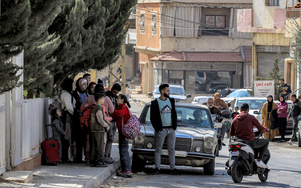 People wait along the side of a road for their ride before evacuating Lebanon's eastern city of Baalbek in the Bekaa Valley on October 30, 2024, after a statement from the Israeli army spokesperson warning residents of incoming strikes on Hezbollah targets. (Photo by Nidal SOLH / AFP)
