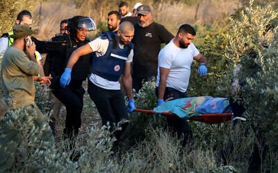 First responders carry the shrouded body of a woman who was killed when a rocket fired from Lebanon hit an area near Kiryat Ata on October 31, 2024. (AHMAD GHARABLI / AFP)