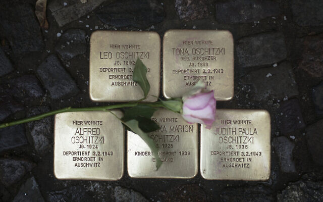 Illustrative: A flower lays on polished so-called 'Stolpersteine' or 'stumbling stones' commemorating people deported and killed by the Nazis, in front of a resident building in Berlin, Germany, November 9, 2021, the 83th anniversary of the Nazis' anti-Jewish pogrom in 1938. (AP Photo/Markus Schreiber) Illustrative: A flower lays on polished so-called 'Stolpersteine' or 'stumbling stones' commemorating people deported and killed by the Nazis, in front of a resident building in Berlin, Germany, November 9, 2021, the 83th anniversary of the Nazis' anti-Jewish pogrom in 1938. (AP Photo/Markus Schreiber)