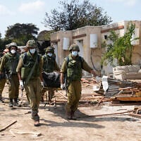 Israeli soldiers carry bodies of Israelis in Kibbutz Kfar Aza on Oct. 10, 2023. (AP Photo/Ohad Zwigenberg, File)