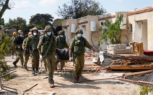 Israeli soldiers carry bodies of Israelis in Kibbutz Kfar Aza on Oct. 10, 2023. (AP Photo/Ohad Zwigenberg, File)