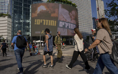 People pass by a sign calling for the release of hostages held in the Gaza Strip by Hamas for nearly a year, in Tel Aviv, Israel, Monday, Sept. 10, 2024. (AP Photo/Ohad Zwigenberg)