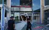 Workers remove broken glass from a damaged building that was hit during Iran's missile attack in Tel Aviv, October 2, 2024. (AP/Ariel Schalit)