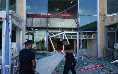 Workers remove broken glass from a damaged building that was hit during Iran's missile attack in Tel Aviv, October 2, 2024. (AP/Ariel Schalit)