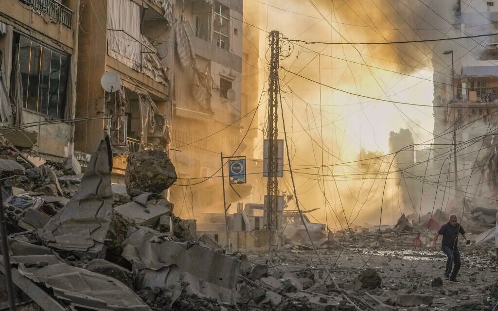 A man runs for cover as smoke rises in after an Israeli airstrike on Hezbollah in the southern Dahiyeh suburb of Beirut, Lebanon, October 4, 2024. (AP Photo/Hassan Ammar)