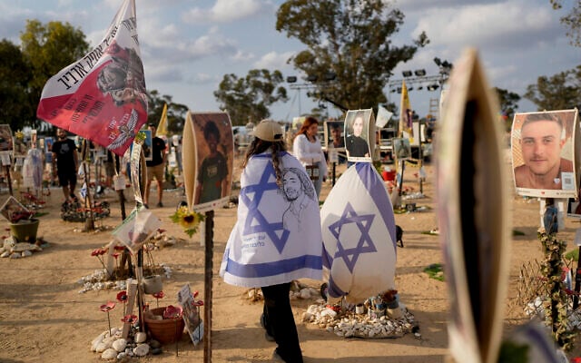 Israelis wrapped in flags visit the site of the October 7 Supernova music festival massacre, on October 6, 2024. (AP/ Ohad Zwigenberg) Israelis wrapped in flags visit the site of the October 7 Supernova music festival massacre, on October 6, 2024. (AP/ Ohad Zwigenberg)