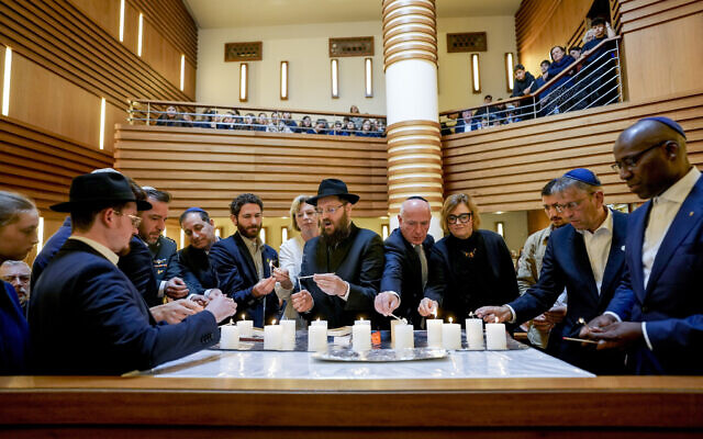 Survivor Alon Gat, Rabi Yehuda Teichtal and Berlin mayor Kai Wegner, centre from left, hold a candle-lighting ceremony marking the first anniversary of the Hamas terror attacks on Israel, at the synagogue of the Chabad community in Berlin, Germany, October 7, 2024. (Markus Schreiber/AP) Survivor Alon Gat, Rabi Yehuda Teichtal and Berlin mayor Kai Wegner, centre from left, hold a candle-lighting ceremony marking the first anniversary of the Hamas terror attacks on Israel, at the synagogue of the Chabad community in Berlin, Germany, October 7, 2024. (Markus Schreiber/AP)