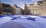 A large Israeli flag is unfurled during a commemoration marking the anniversary of the Oct. 7, 2023, Hamas terror attack on Israel, in Amsterdam, Netherlands, October 7, 2024. (Peter Dejong/AP)