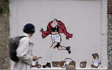 A man walks past the vandalized mural 'October 7th, Escape' by Italian artist aleXsandro Palombo, in downtown Milan, Italy, October 7, 2024. (AP Photo/ Antonio Calanni)