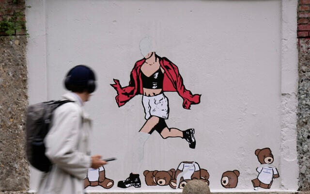 A man walks past the vandalized mural 'October 7th, Escape' by Italian artist aleXsandro Palombo, in downtown Milan, Italy, October 7, 2024. (AP Photo/ Antonio Calanni)
