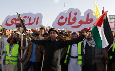 A Houthi supporter raises a Palestinian flag and a machine gun, during a rally to celebrate the first anniversary of Hamas's October 7 attack on Israel, in Sanaa, Yemen, October 7, 2024. The Arabic reads 'Al-Aqsa Floods,' Hamas's name for the attack. (AP/Osamah Abdulrahman)