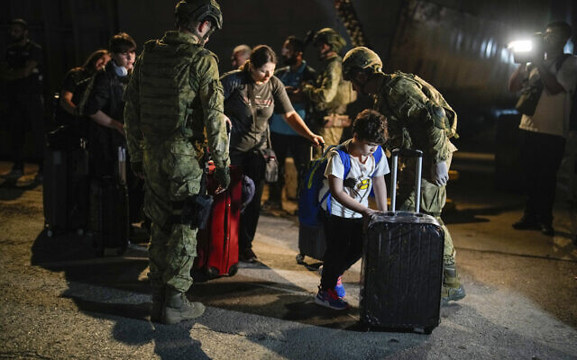 Turkish citizens walk to board Turkish military ships evacuating them from Lebanon to Turkey, in Beirut port on October 9, 2024. (AP Photo/Emrah Gurel)