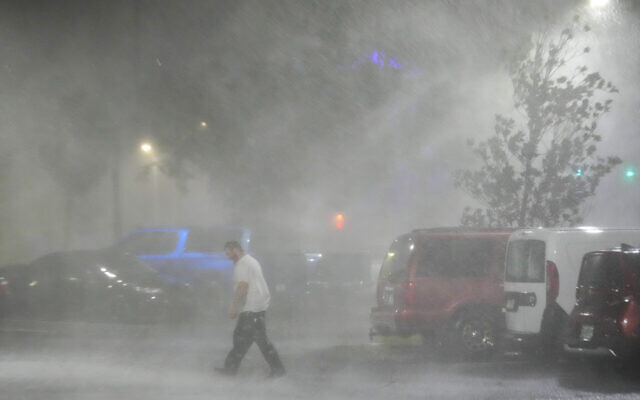 Max Watts, of Buford, Ga., walks in the parking lot to check on a trailer parked outside the hotel where he is riding out Hurricane Milton with coworkers, Wednesday, Oct. 9, 2024, in Tampa, Fla. Watts, who works for a towing company, was deployed with colleagues to Florida to aid in the aftermath of the storm. (AP Photo/Julio Cortez) Max Watts, of Buford, Ga., walks in the parking lot to check on a trailer parked outside the hotel where he is riding out Hurricane Milton with coworkers, Wednesday, Oct. 9, 2024, in Tampa, Fla. Watts, who works for a towing company, was deployed with colleagues to Florida to aid in the aftermath of the storm. (AP Photo/Julio Cortez)