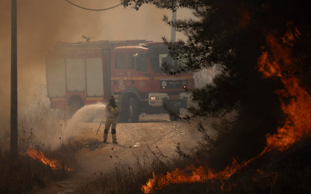 A firefighter works to extinguish a fire after a rocket fired from Lebanon hit an area near northern town of Rosh Pina, October 20, 2024. (AP Photo/Leo Correa)
