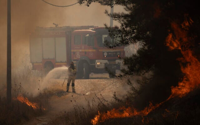 A firefighter works to extinguish a fire after a rocket fired from Lebanon hit an area near northern town of Rosh Pina, October 20, 2024. (AP Photo/Leo Correa)