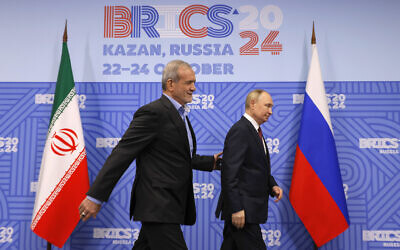 Russian President Vladimir Putin, right, and Iranian President Masoud Pezeshkian walk during their meeting on the sidelines of the BRICS summit in Kazan, Russia, Wednesday, Oct. 23, 2024. (Maxim Shemetov, Pool Photo via AP)