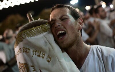 Illustrative image: A Jewish man carries a Torah scroll during Simhat Torah celebrations at Rabin Square, Tel Aviv, on October 21, 2019. (Tomer Neuberg/Flash90)