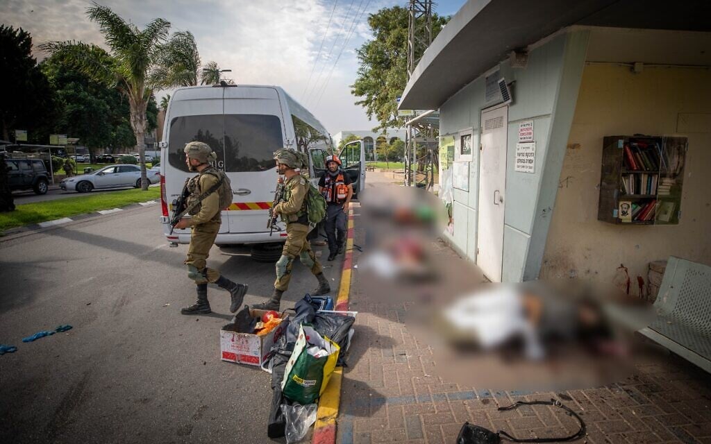 Israeli soldiers walk next to bodies of people murdered by Hamas terrorists lying outside the shelter in the southern Israeli city of Sderot, October 7, 2023. (Photo by Jamal Awad/Flash90)