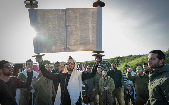 IDF Reserve soldiers and Orthodox Jews take part in prayer and the weekly reading of a Torah Scroll at dawn just before a military exercise on the Golan Heights, April 1, 2024. (Michael Giladi/ Flash90)