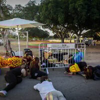 People take cover as sirens warn of an incoming missile fired from Yemen, at Yarkon Park in Tel Aviv, October 7, 2024. (Miriam Alster/Flash90)