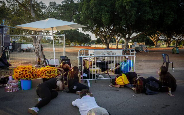 People take cover as sirens warn of an incoming missile fired from Yemen, at Yarkon Park in Tel Aviv, October 7, 2024. (Miriam Alster/Flash90)