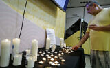 An Israeli man lights a memorial candle to mark the first anniversary of the October 7 attack at a cultural center in the northern city of Katzrin, October 7, 2024. (Michael Giladi/Flash90)