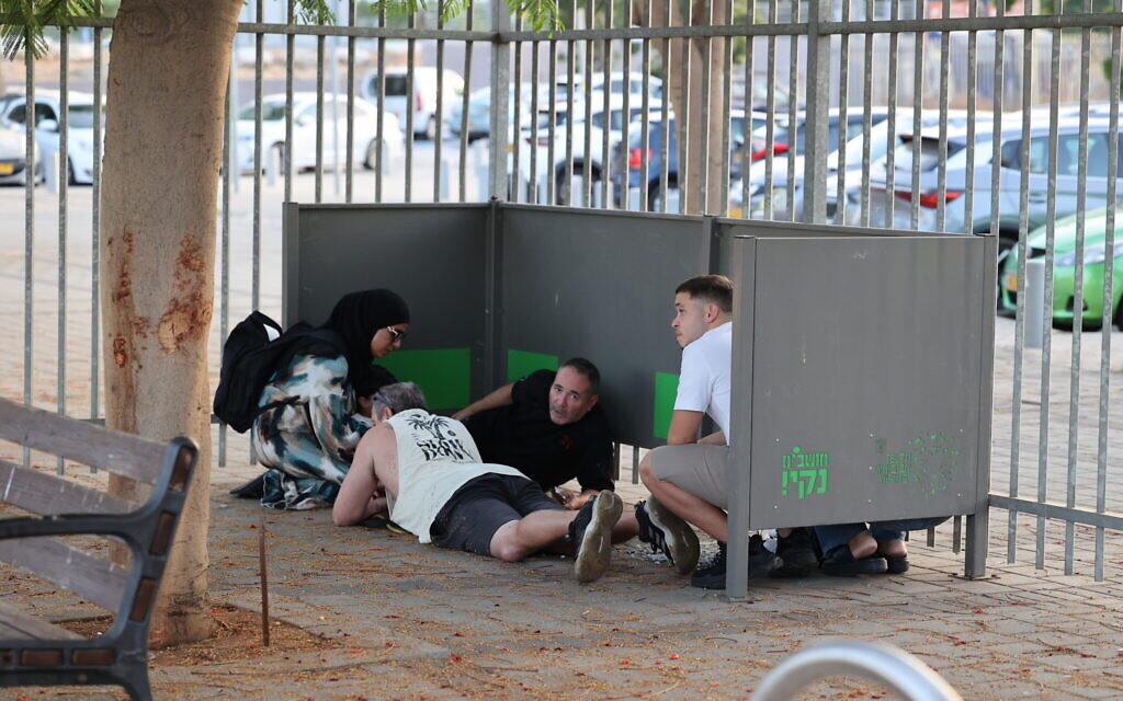 Israelis take cover as sirens warn of an incoming missile fired from Lebanon, in Holon, October 14, 2024. (Yossi Aloni/Flash90)