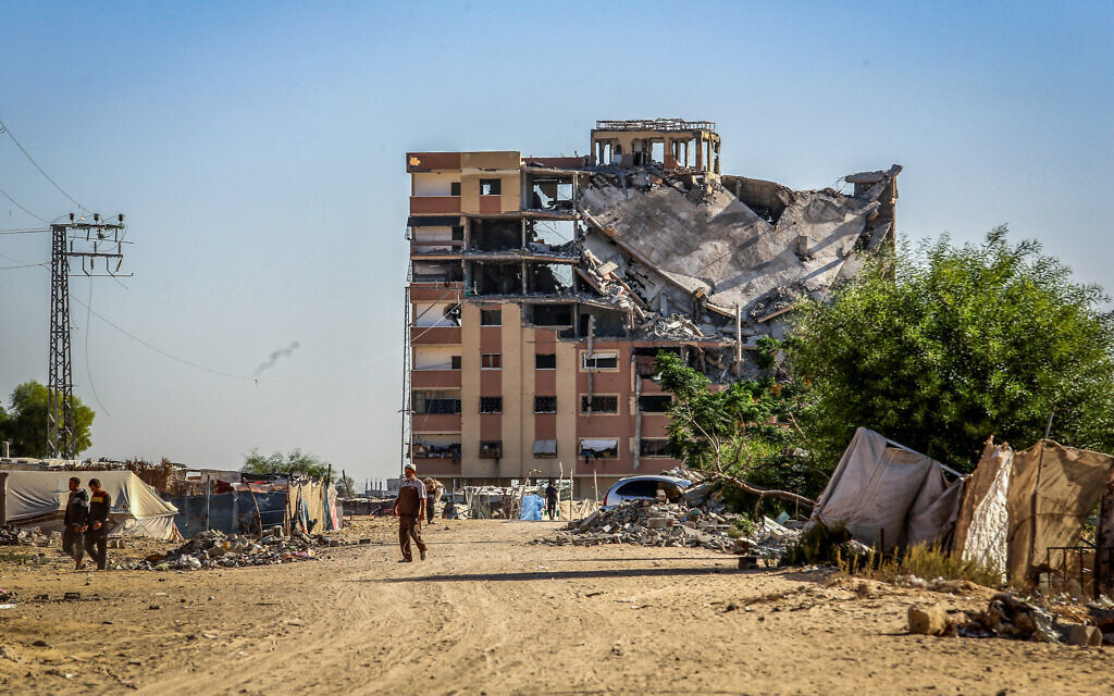 Illustrative: Palestinians near destroyed buildings in Khan Younis, in the southern Gaza Strip, on October 21, 2024. (Abed Rahim Khatib/Flash90)