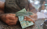 A money changer counts notes at his shop in the Lebanese capital Beirut on September 22, 2022. (ANWAR AMRO / AFP)