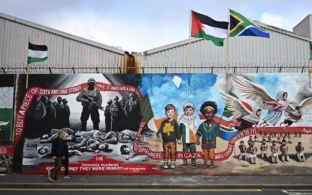 Pedestrians walk past a mural depicting dark and shadowy Israeli soldiers on the International Wall on the Falls Road in Belfast, Northern Ireland, March 19, 2024. (Paul Ellis/AFP) Pedestrians walk past a mural depicting dark and shadowy Israeli soldiers on the International Wall on the Falls Road in Belfast, Northern Ireland, March 19, 2024. (Paul Ellis/AFP)