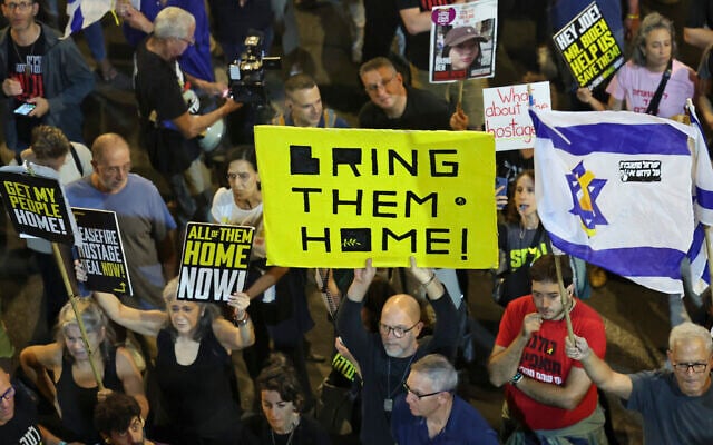 Demonstrators hold placards and wave Israeli flags during an anti-government protest calling for action to secure the release of Israeli hostages held captive since Hamas's October 7, 2023, massacre, Tel Aviv, November 2, 2024. (Jack Guez/AFP)