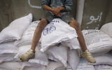 FILE: A Palestinian child sits on top of sacks of flour at a United Nations Relief and Works Agency (UNRWA) aid distribution centre in Deir el-Balah in the central Gaza Strip on November 3, 2024. (Eyad BABA / AFP)