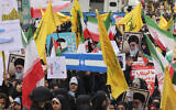 Women wave Iranian, Palestinian and Hezbollah flags as they carry a mock coffin bearing the Israeli flag during a rally outside the former US embassy in Tehran on November 3, 2024 (ATTA KENARE / AFP)