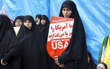 Women hold placards during a rally outside the former US embassy in Tehran as Iranians mark the 45th anniversary of the start of the Iran hostage crisis, on November 3, 2024. (Atta Kenare/AFP)