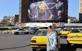 A young woman crosses a main road in front of an anti-Israel and US billboard depicting an Israeli soldier receiving military supplies from the United States with a Farsi headline reading "the American Rabid Dog" in central Tehran's Valiasr Square on November 6, 2024. (ATTA KENARE / AFP)