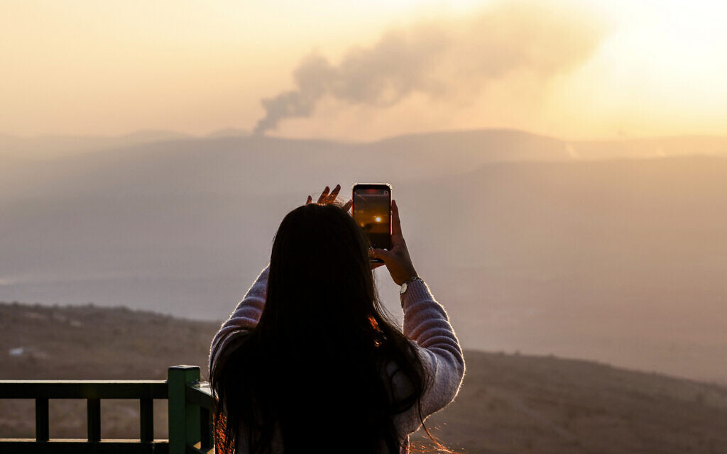 A woman in northern Israel snaps a picture of smoke billowing after rockets fired from Lebanon targeted Moshav Avivim near the border on November 6, 2024 (Photo by Jalaa MAREY / AFP)