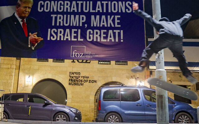 A youth performs a trick on a skateboard under a banner congratulating US President-elect Donald Trump on winning the US presidential election, in Jerusalem on November 7, 2024. (Ahmad Gharabli/AFP)