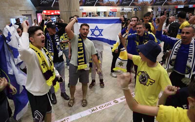 Maccabi Tel Aviv fans carry flags as they wait for the arrival of their friends and family members from Amsterdam, at Ben Gurion International Airport on November 8, 2024. (Jack Guez/AFP)