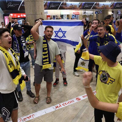 Maccabi Tel Aviv fans carry flags as they wait for the arrival of their friends and family members from Amsterdam, at Ben Gurion International Airport on November 8, 2024. (Jack Guez/AFP)