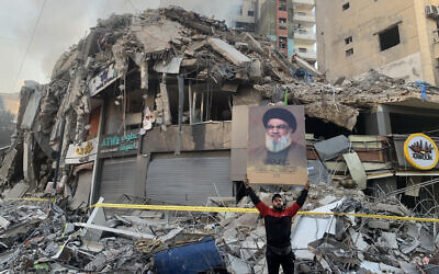 A man flashes a portrait of slain Hezbollah chief Hassan Nasrallah in front of the rubble of a building at the site of an Israeli airstrike in Beirut's southern suburbs, on November 12, 2024, amid the ongoing war between Israel and Hezbollah. (AFP)