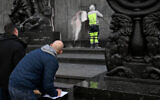 Law enforcement officers write a report as a worker cleans the red-black paint stain on a monument to the Warsaw Ghetto Uprising in Warsaw on November 15, 2024 (Sergei GAPON / AFP)