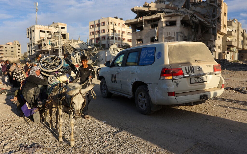 A convoy led by a United Nations vehicle drives past displaced Palestinians fleeing Beit Lahiya in the northern Gaza Strip on the main Salah al-Din road on November 17, 2024. (Omar Al-Qattaa/AFP)