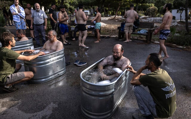 Volunteers of ZAKA, a unique rescue and recovery group whose job is to collect the remains of the dead for burial in accordance with Jewish religious law, are guided by therapists as they take an ice bath during an organized activity session aimed at dealing with trauma from Hamas's October 7, 2023, terror onslaught, in Nes Harim, near Jerusalem, on November 17, 2024. (Photo by Menahem KAHANA / AFP)